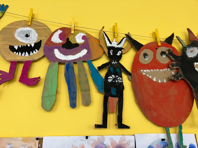 Bunte Monsterfiguren aus Pappe hängen an einer Schnur.